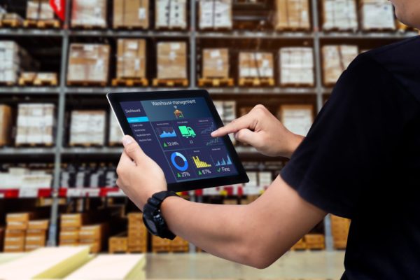 A man using a tablet to access a warehouse management system