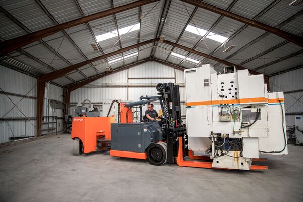 A high-capacity Toyota forklift transporting a large machine
