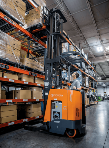 A reach truck operator extending the forks to retrieve a pallet from racking