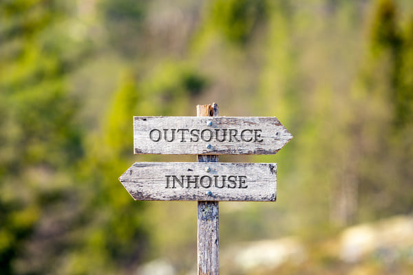 A sign post displaying two signs reading "Outsource" and "Inhouse" signifying different way to reduce lead time