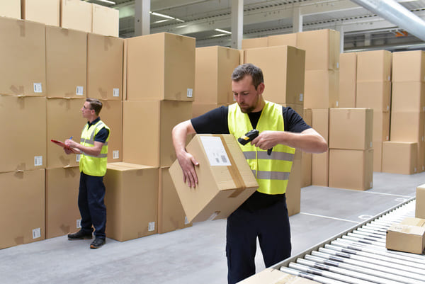 A warehouse worker holding a cardboard box and scanning it with an RF scanner