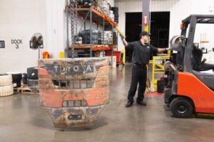 A forklift technician removing a forklift back to refurbish it