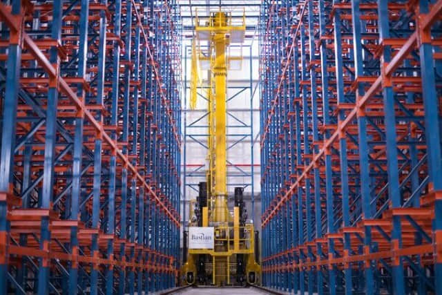 A Bastian Solutions automated storage and retrieval system (ASRS) crane in an empty aisle between racking