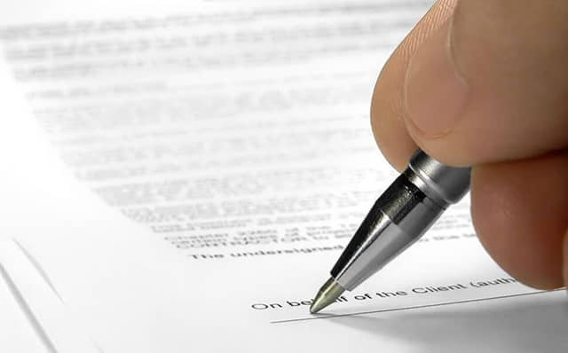 A person signing a written agreement with a pen
