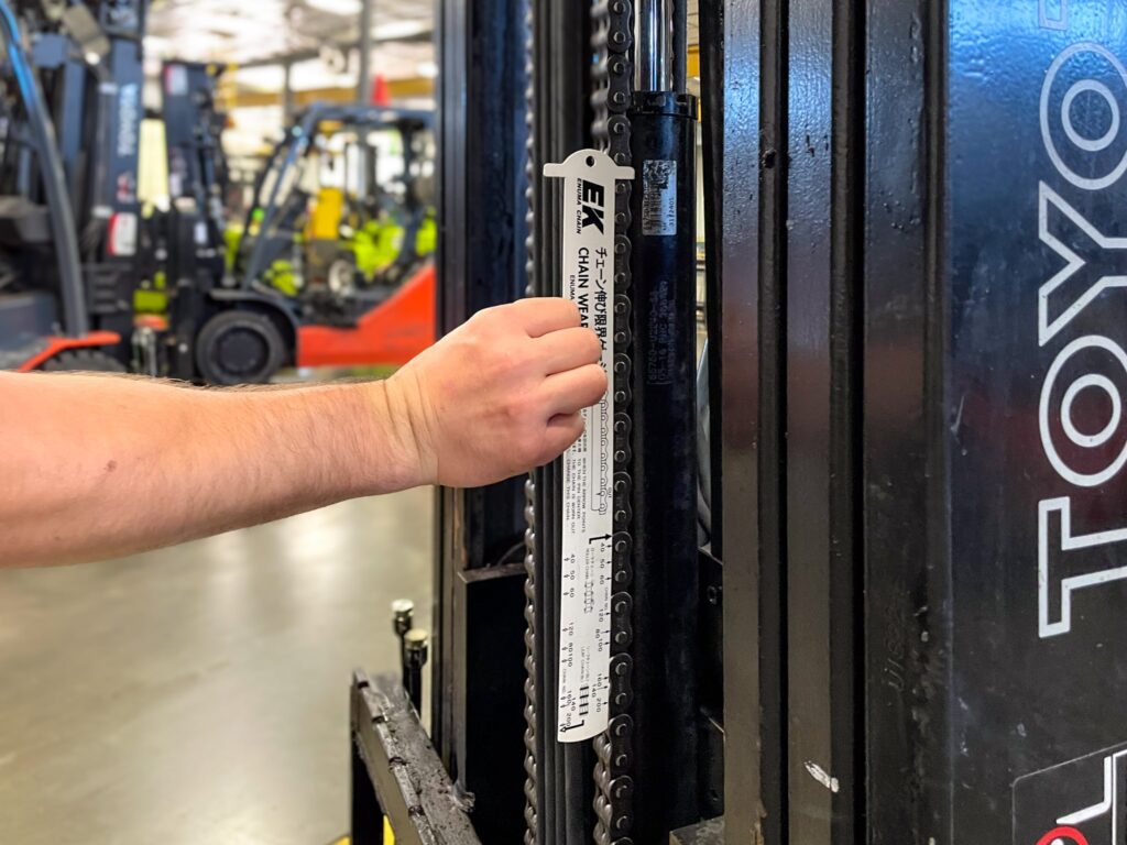 person inspecting forklift chains