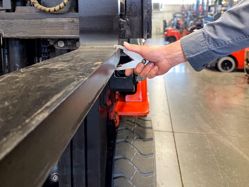 person inspecting forklift forks